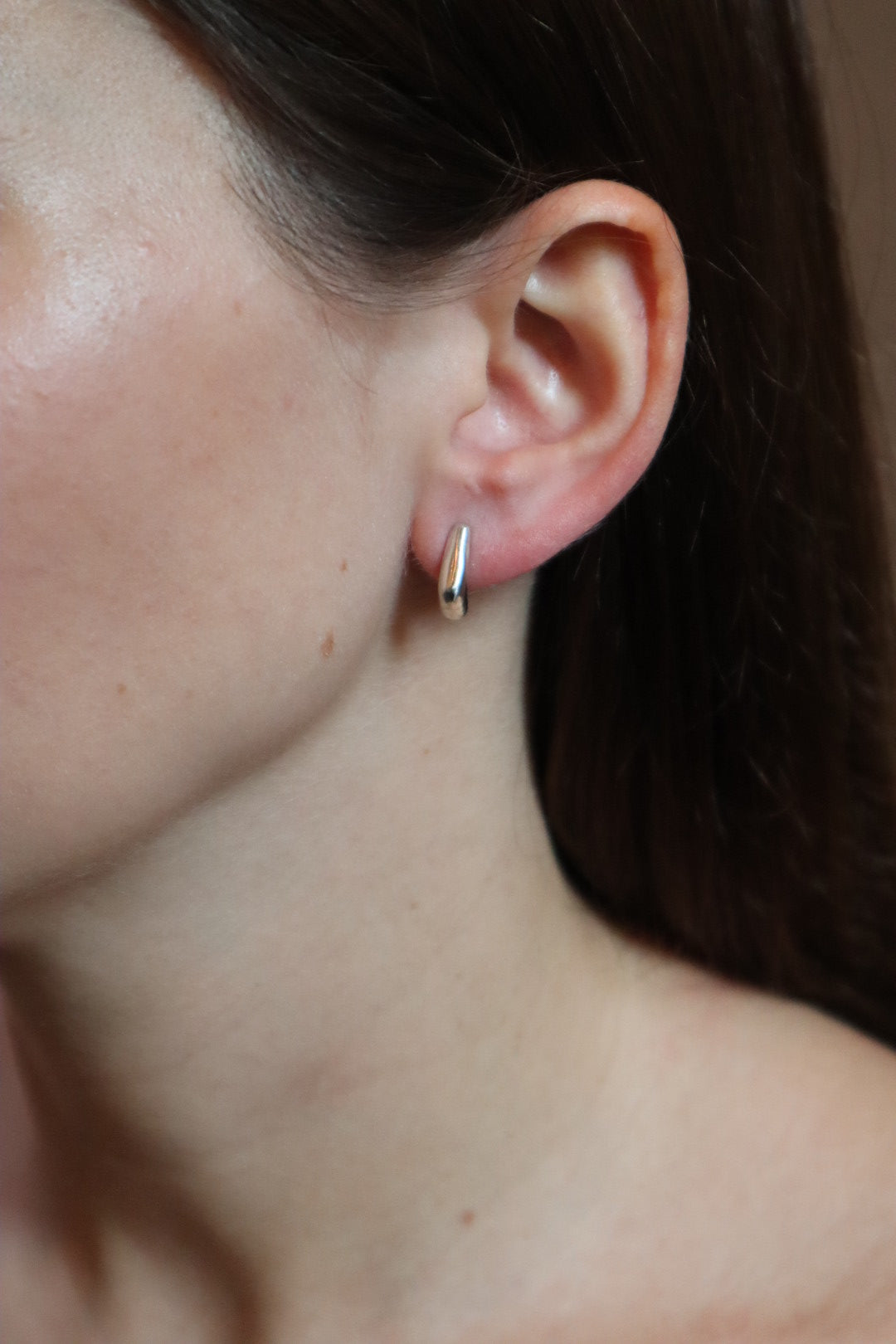 Close-up of an ear with a small earring on a blurred background